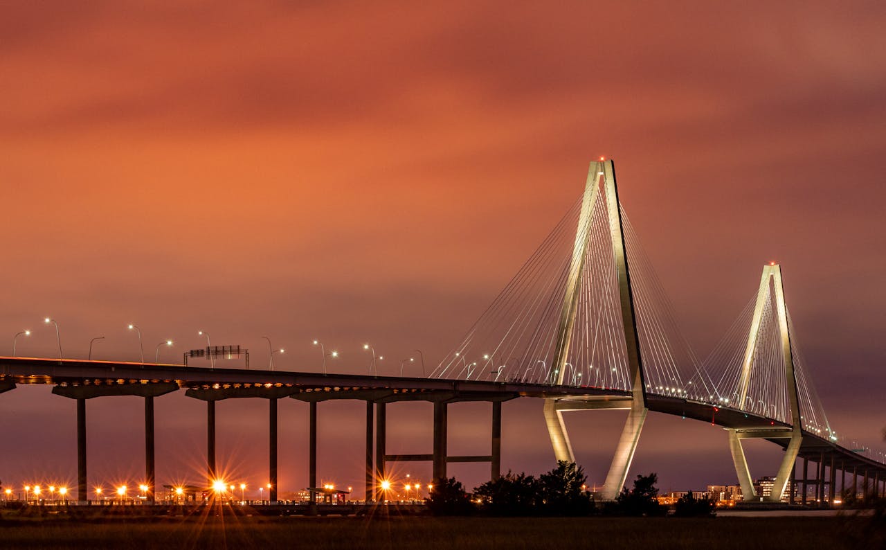 Stunning view of the illuminated Arthur Ravenel Jr. Bridge in Charleston, SC during sunset.
