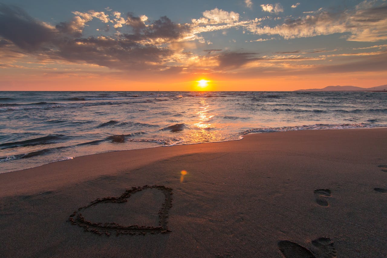 Services Beautiful sunset over ocean with a heart shape in the sand, perfect for romantic themes.