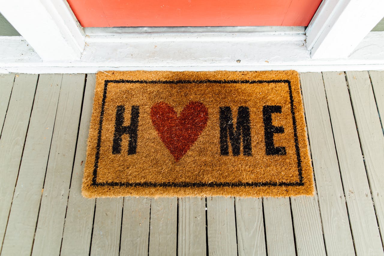 About Doormat with 'Home' written and heart symbol on wooden porch.