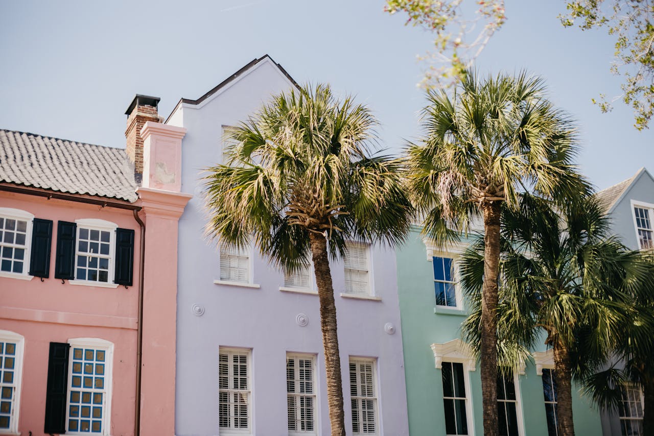 Vibrant pastel homes and palm trees on a sunny street in Charleston.